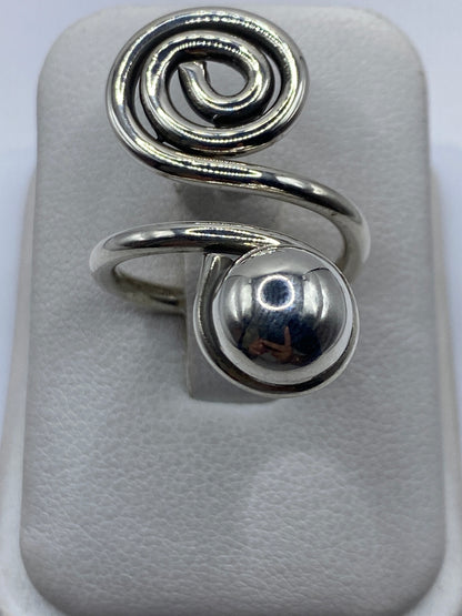 Anillo de plata calado ajustable con diseño en espiral en la mano de una mujer