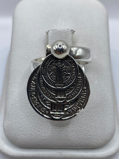 Anillo religioso de plata .925 ajustable sobre estuche blanco, visto de frente con detalle de diseño sagrado