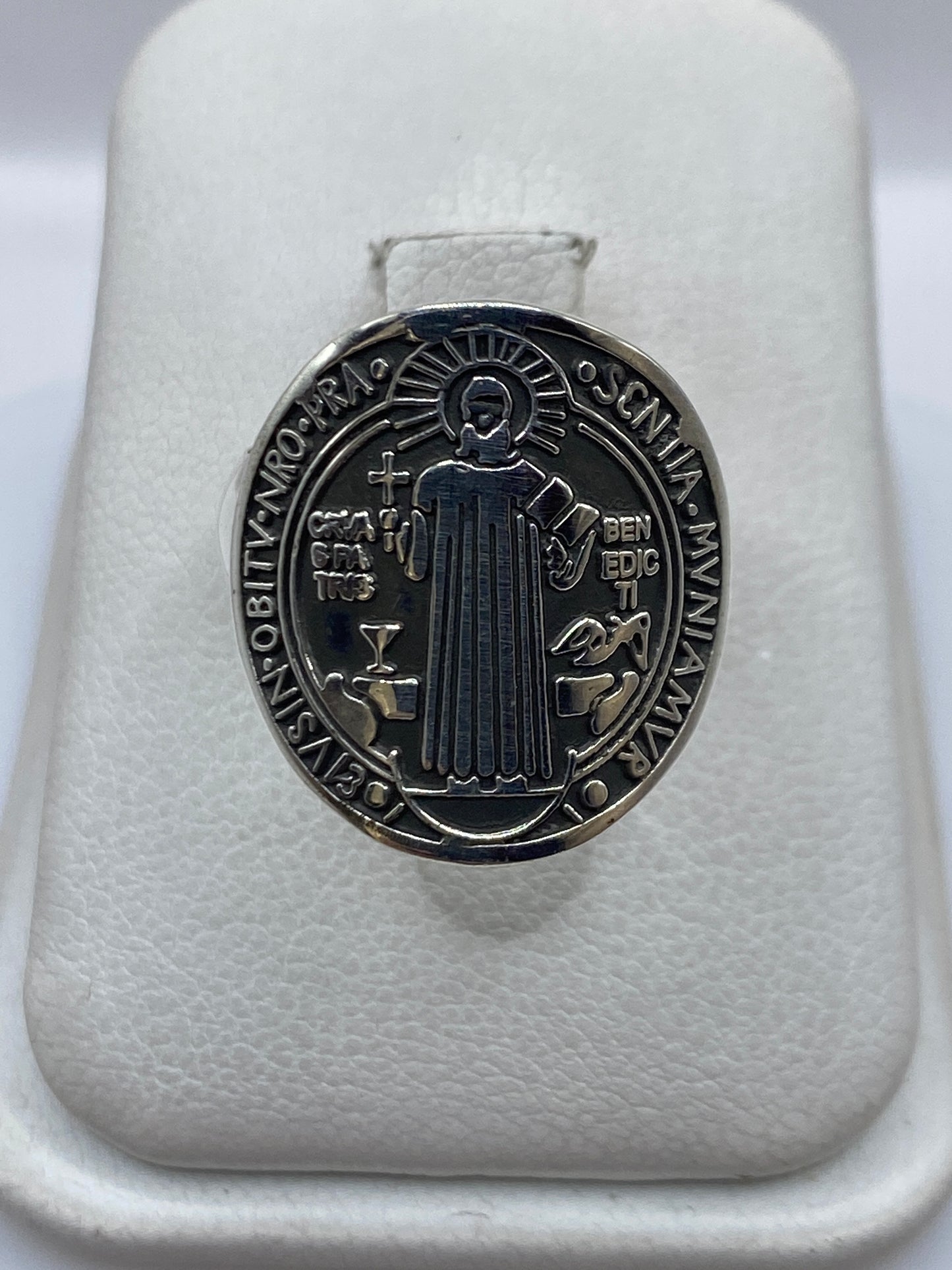 Anillo de plata con medallón Saint Benedict, visto de frente sobre soporte blanco