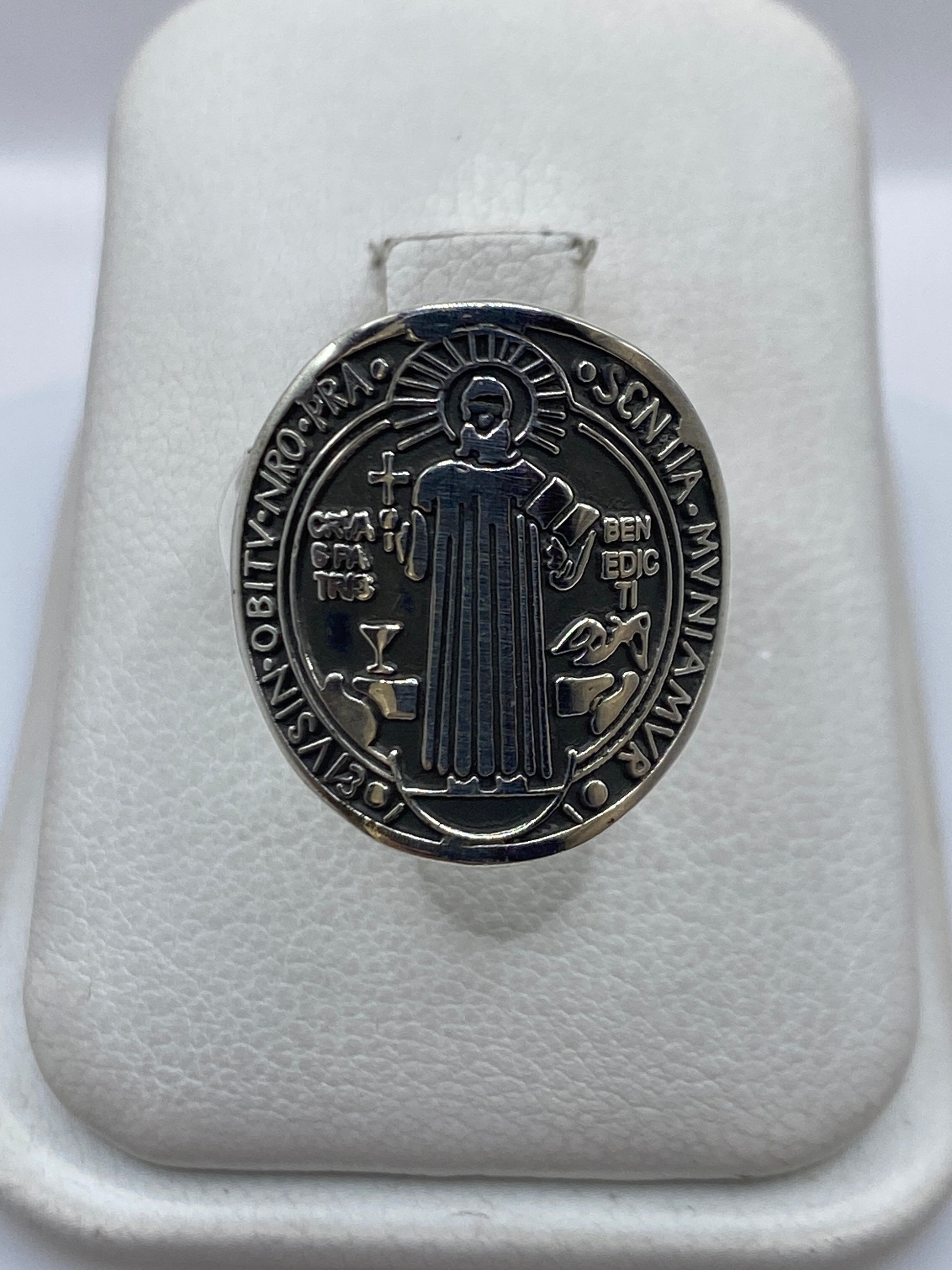 Anillo de plata con medallón Saint Benedict, visto de frente sobre soporte blanco