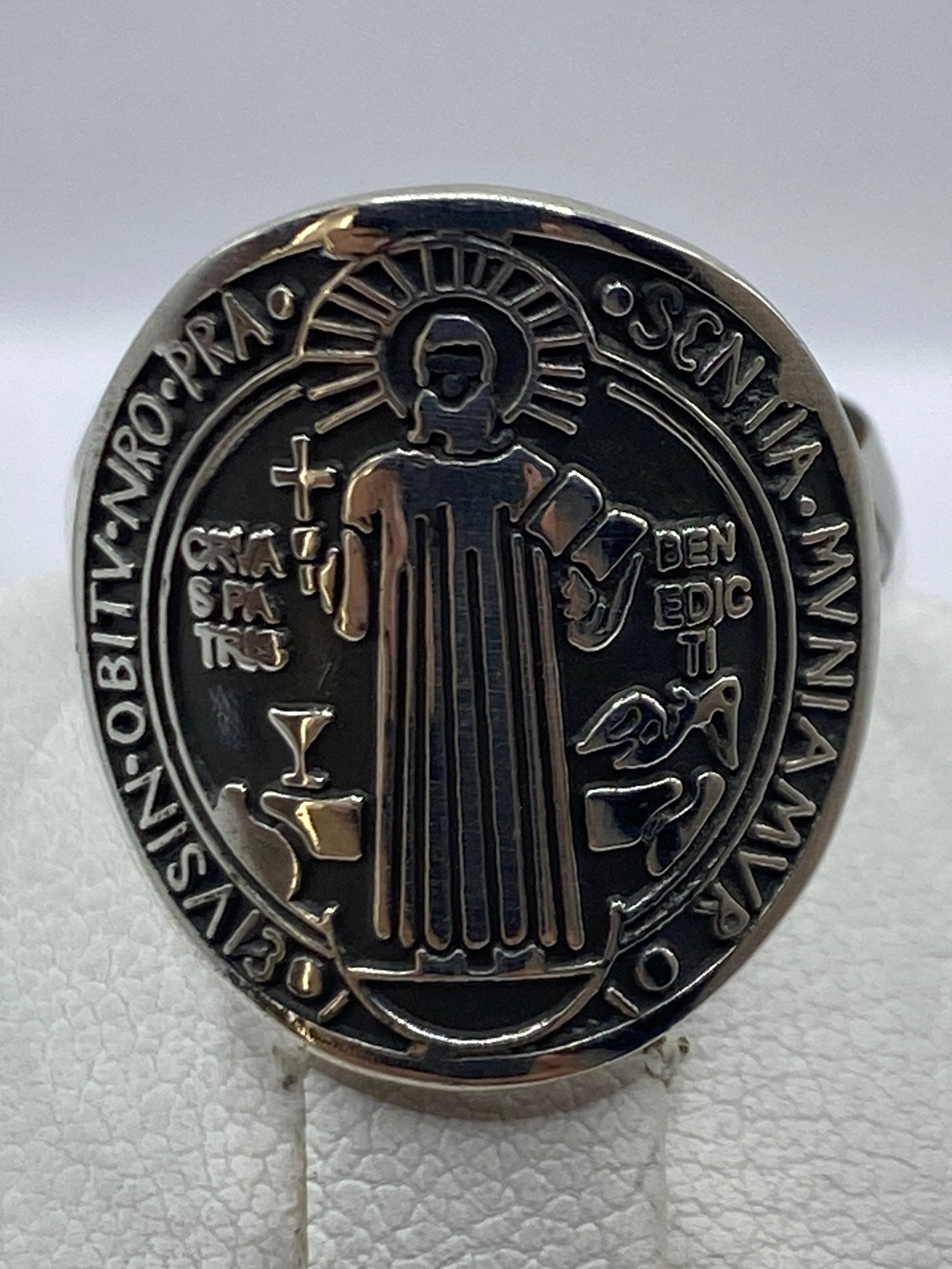 Anillo de plata en la mano mostrando el medallón clásico de San Benito