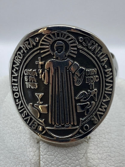 Anillo de plata en la mano mostrando el medallón clásico de San Benito