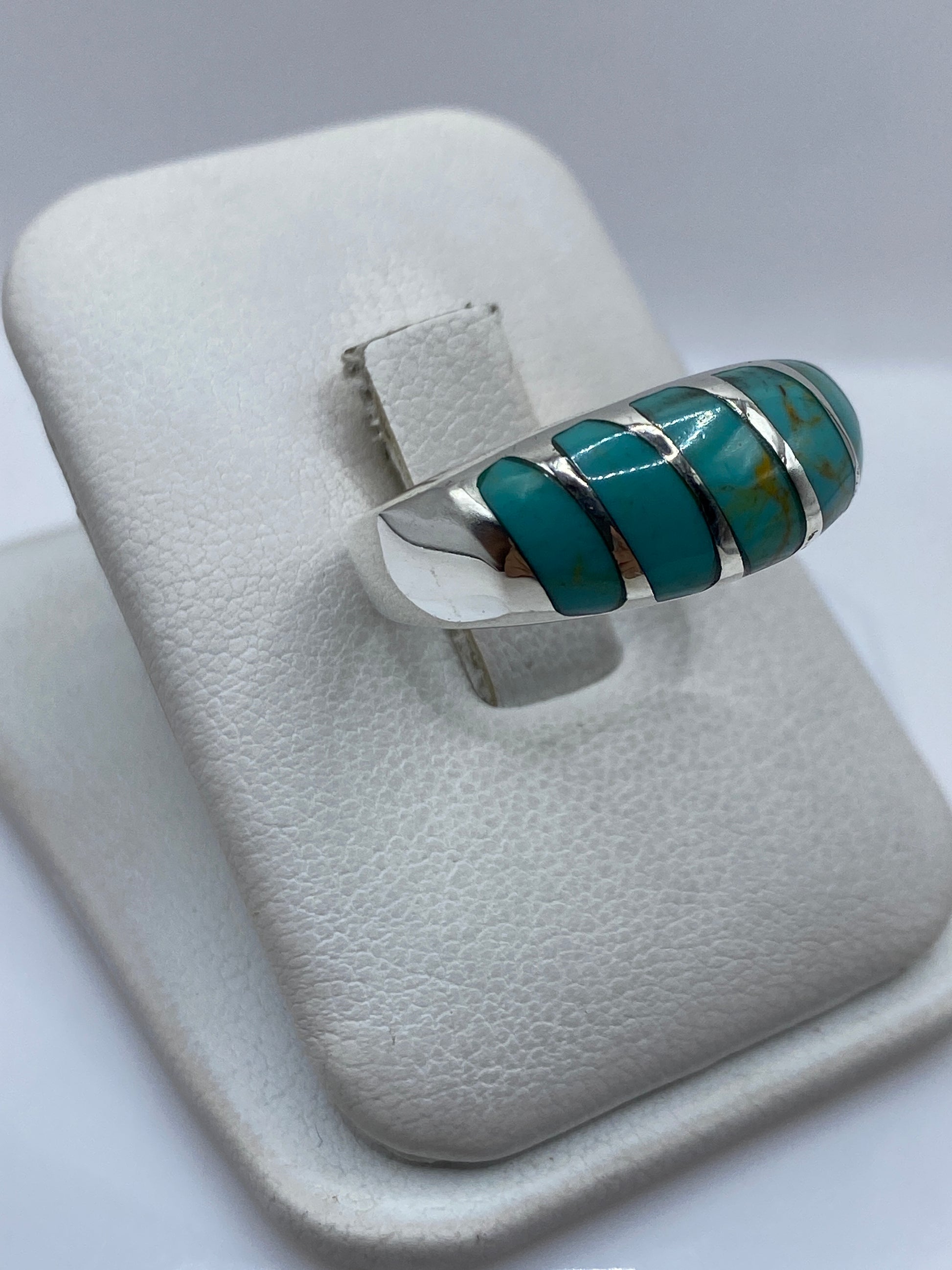 Detalle lateral del anillo unisex mostrando el engaste individual de cada turquesa en plata