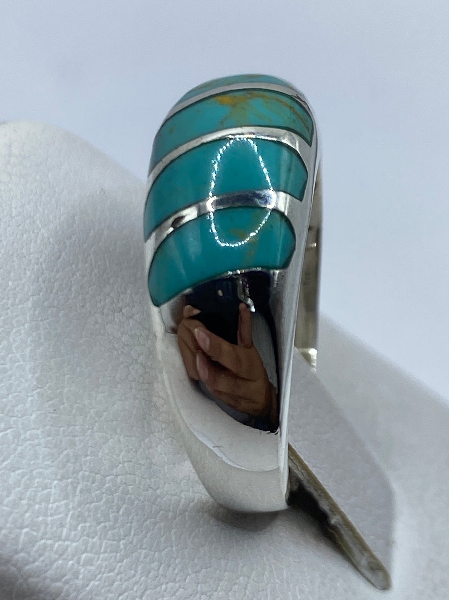 Anillo en la mano de una mujer mostrando el tono azul cielo de la turquesa y el acabado pulido de la plata