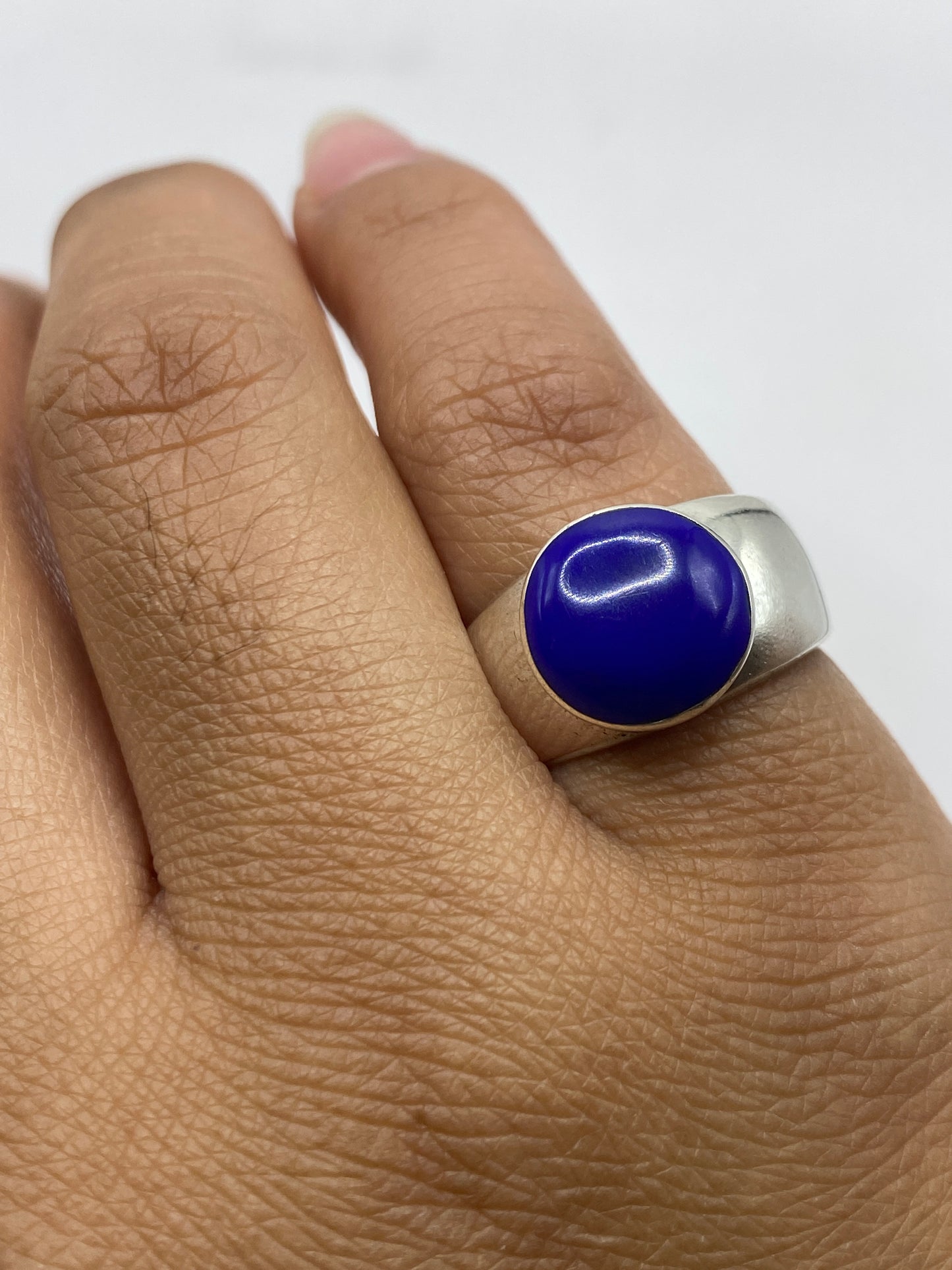 Anillo sobre superficie reflectante, piedra azul intenso en primer plano