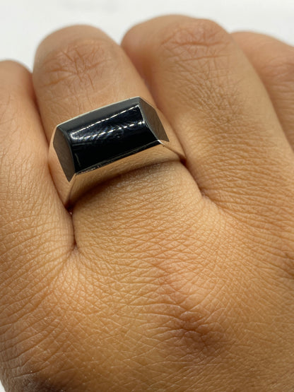 Anillo sobre fondo gris neutro destacando el brillo de la plata y la profundidad del onix