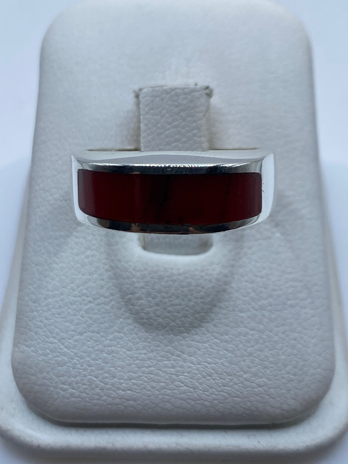 Anillo de plata .925 con coral rojo engastado en la mano de una persona
