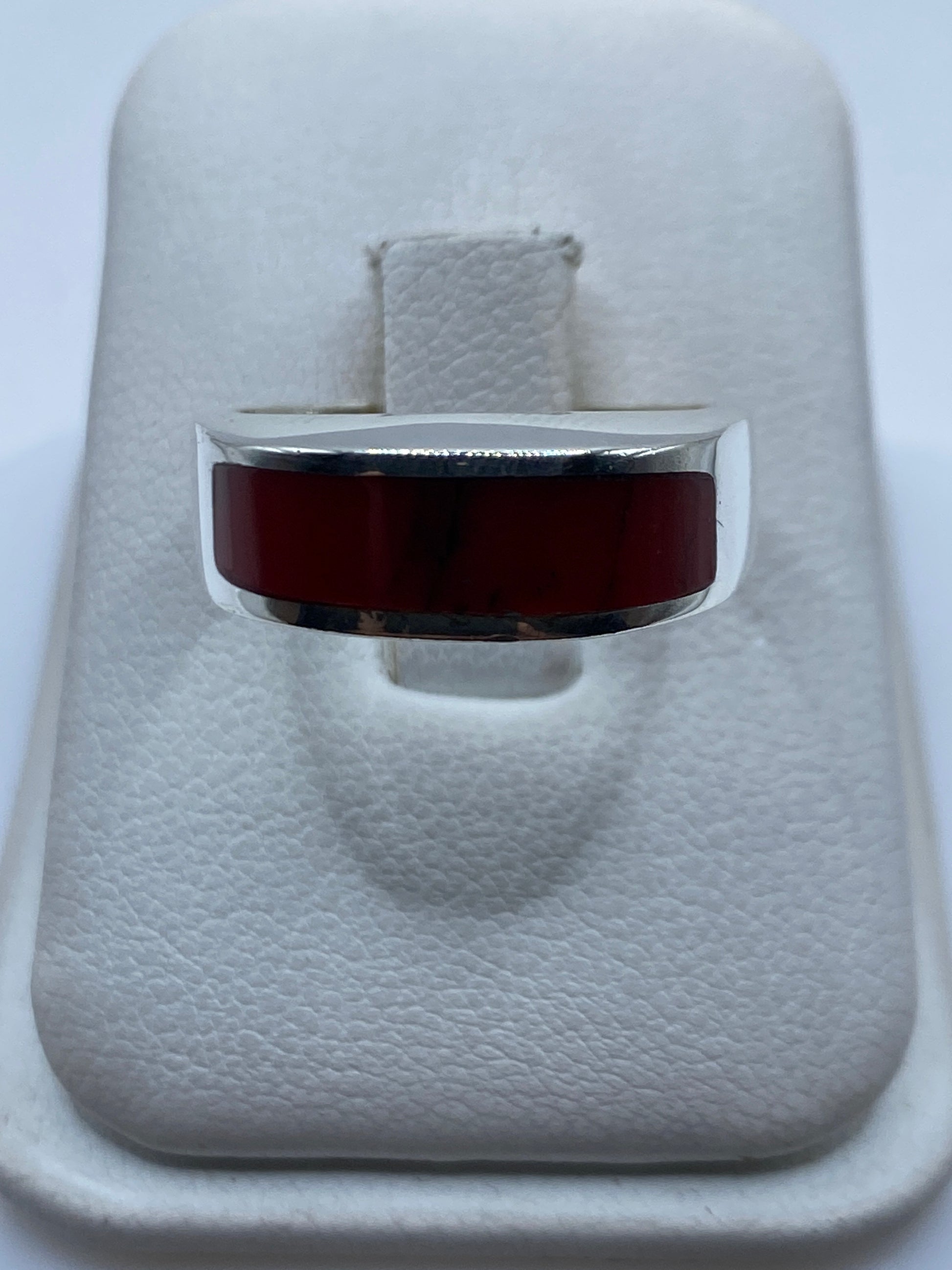 Anillo de plata .925 con coral rojo engastado en la mano de una persona
