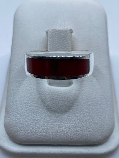 Anillo de plata .925 con coral rojo engastado en la mano de una persona
