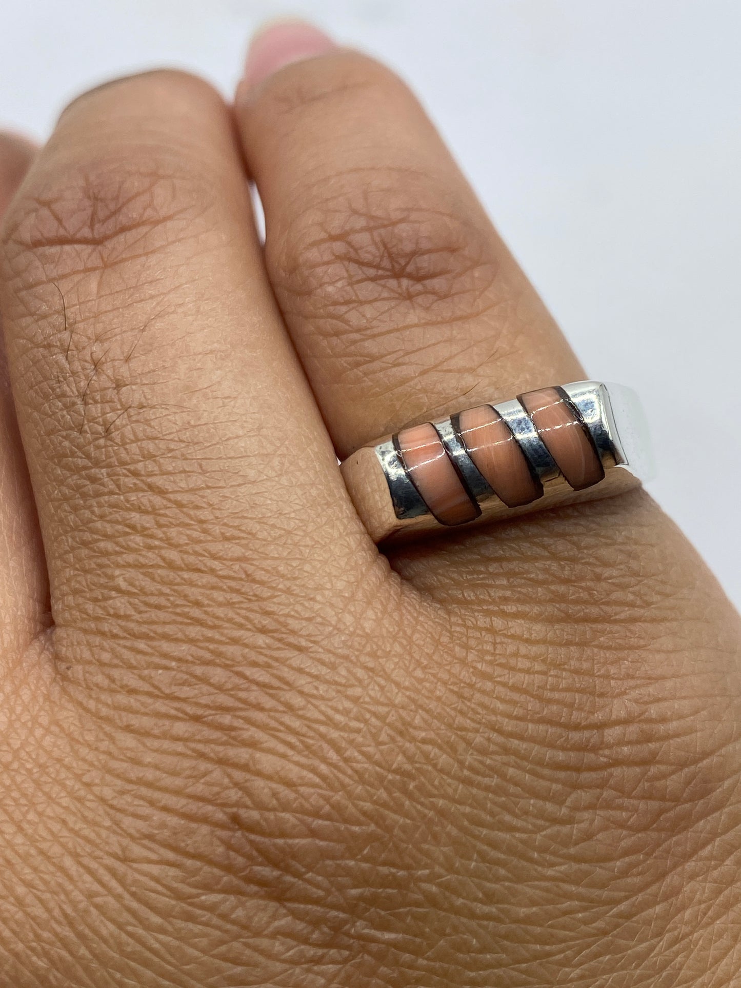 Anillo en la mano de una mujer mostrando el brillo del coral y la plata juntos