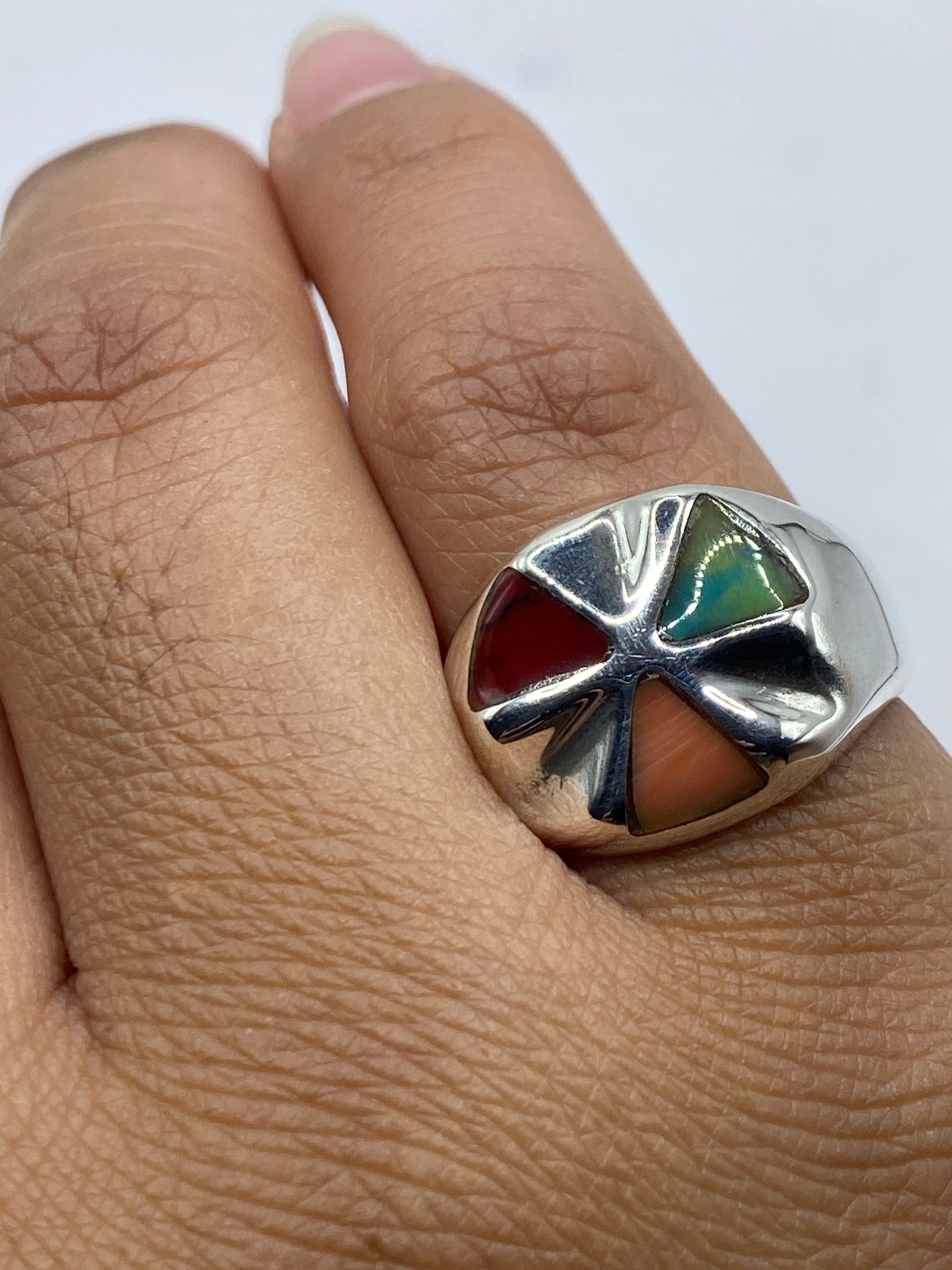 Anillo en la mano mostrando el brillo del coral rojo y el pulido de la plata