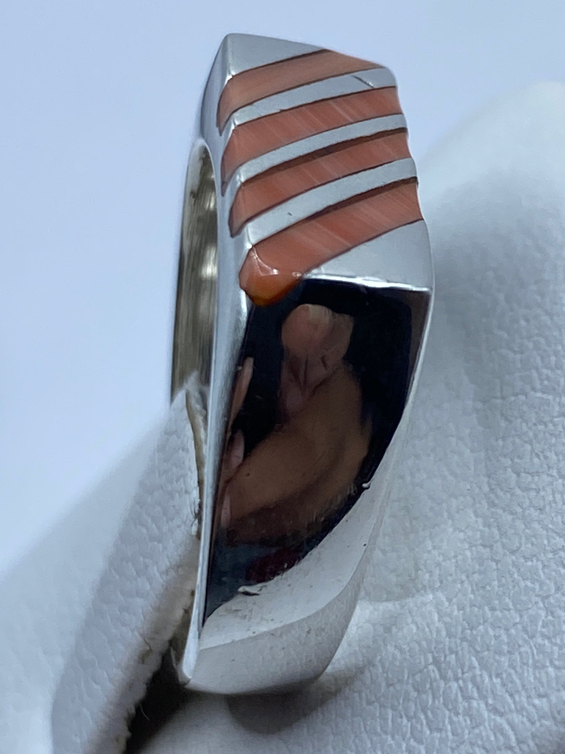 Anillo de coral y plata puesto en dedo, tono naranja rojizo cálido bajo luz natural