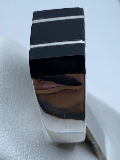 Anillo puesto en dedo de hombre, ónix negro brillante con bandas de plata entre piedras