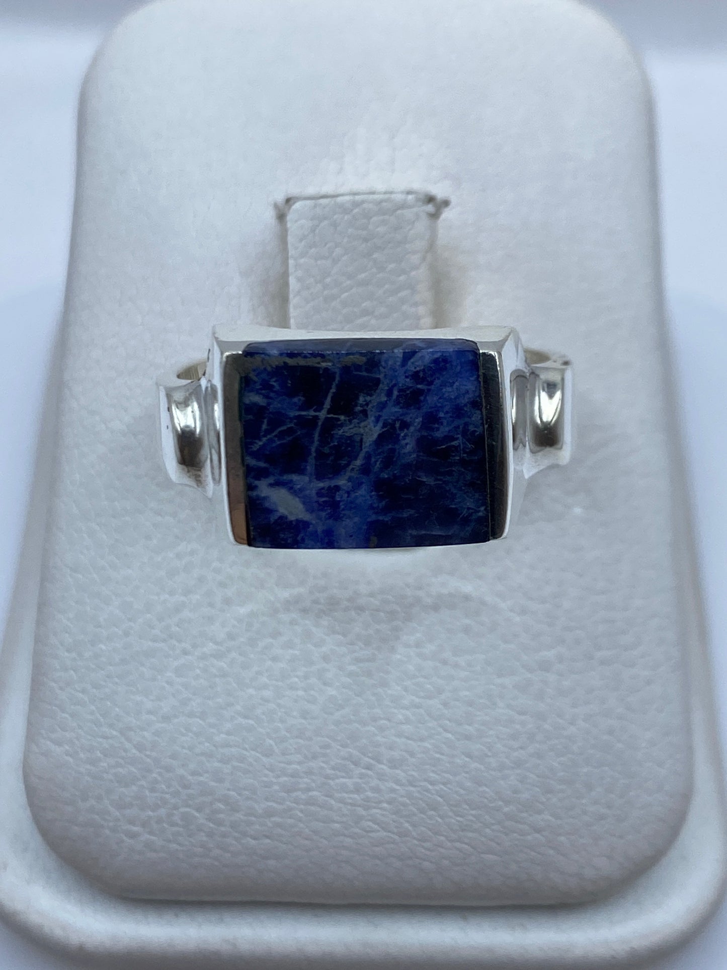 Anillo de plata .925 con piedra azul engastada, visto de frente en estuche blanco