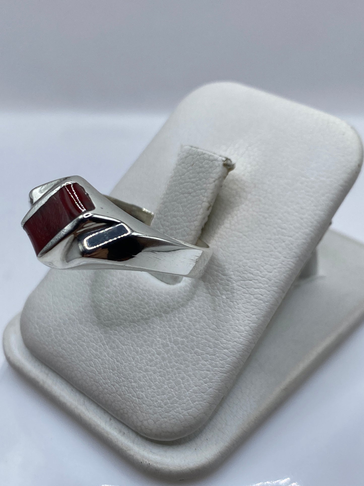 Anillo de plata coral rojo en mano, mostrando el brillo del pulido y la profundidad del engaste