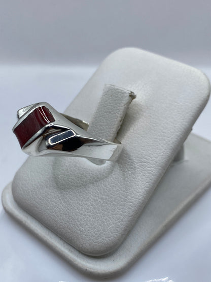 Anillo de plata coral rojo en mano, mostrando el brillo del pulido y la profundidad del engaste