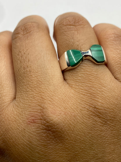Anillo en mano femenina, malaquita verde brillando bajo luz natural