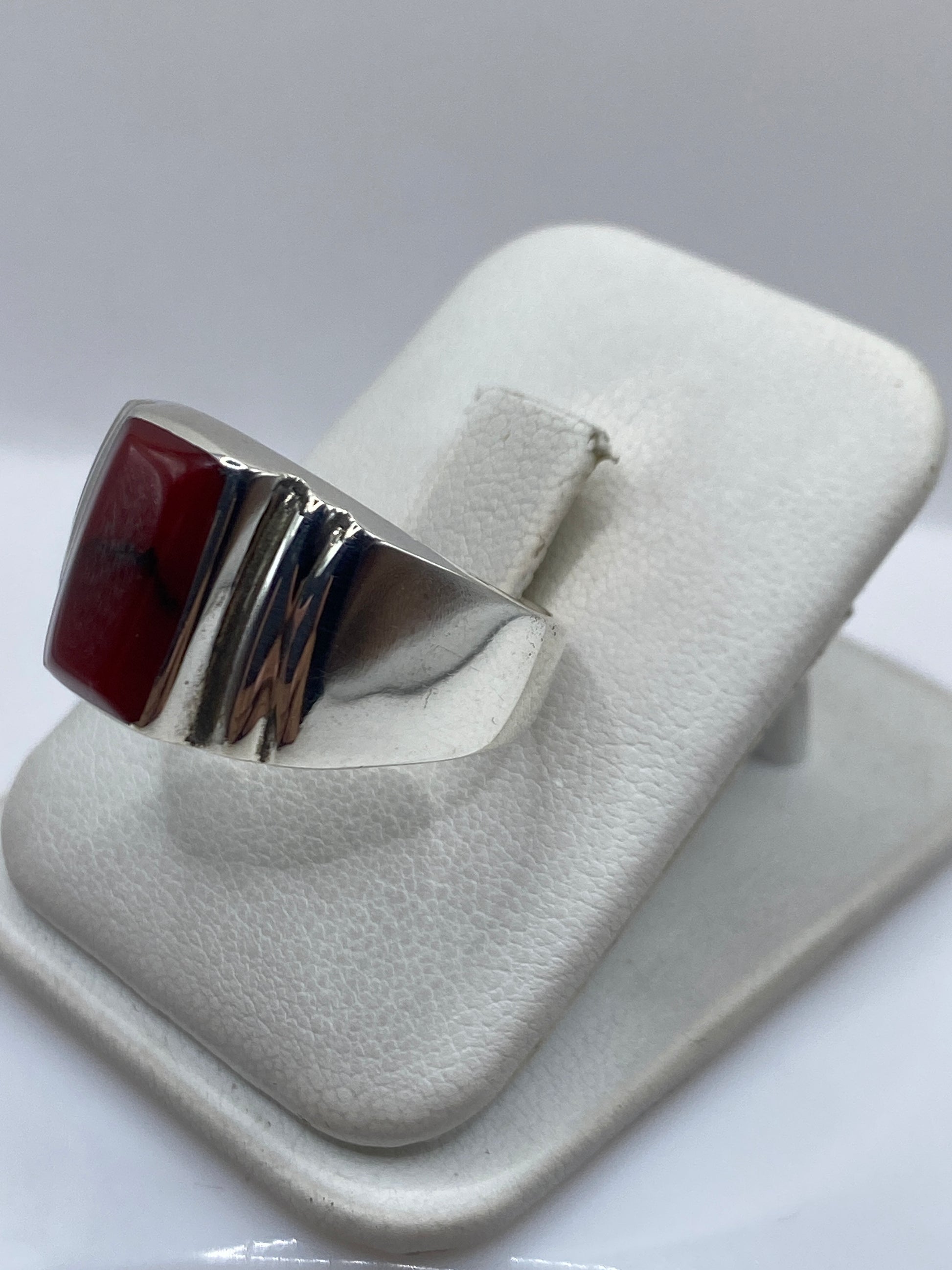 Detalle lateral del anillo mostrando el engaste a mano del coral y las láminas de plata pulida