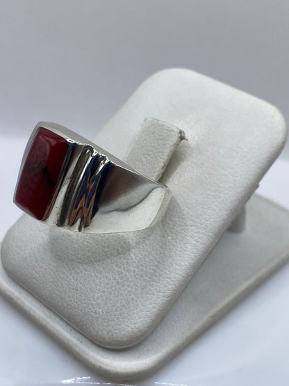 Detalle lateral del anillo mostrando el engaste a mano del coral y las láminas de plata pulida
