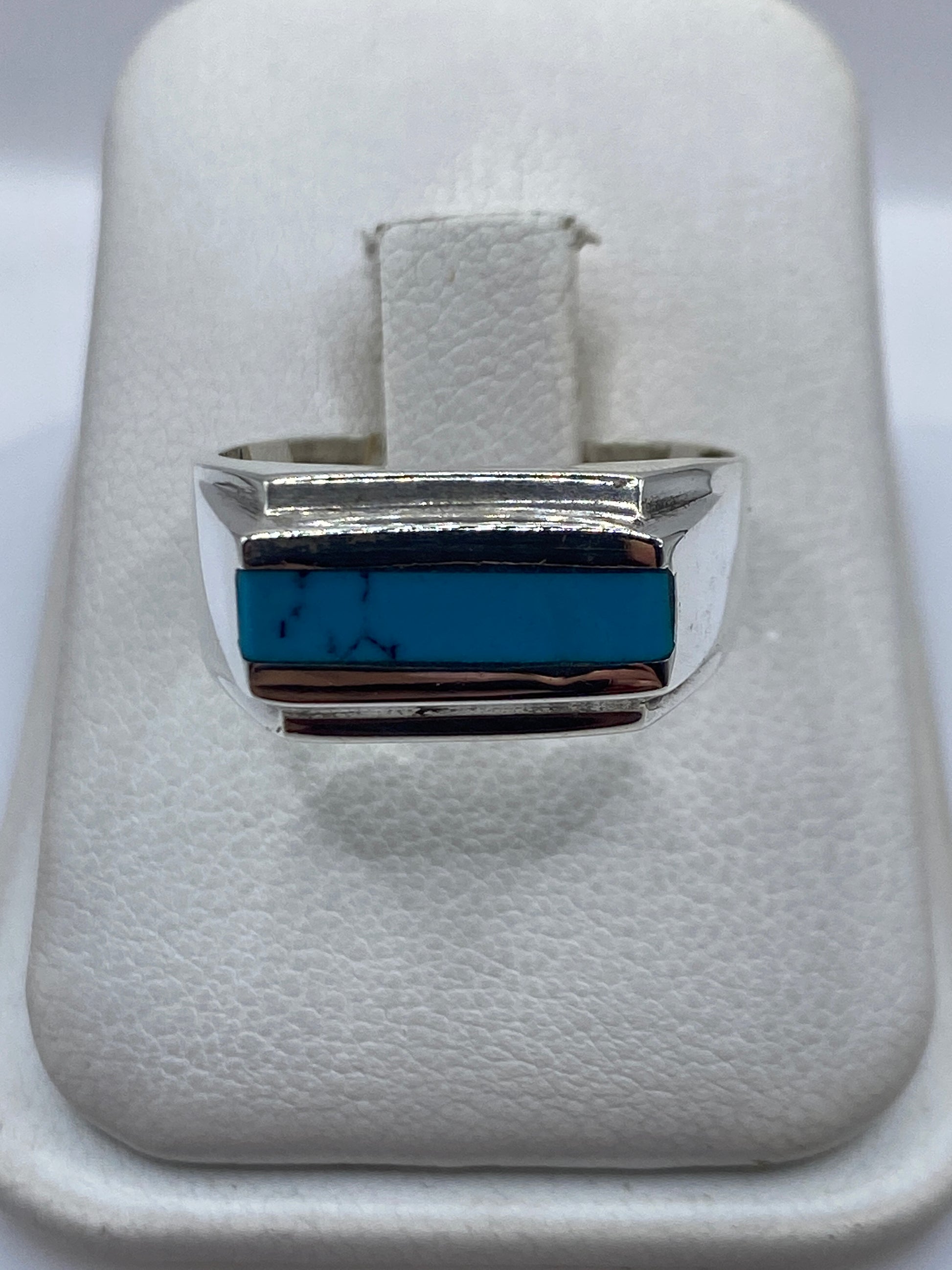Anillo de plata con turquesa azul cielo en bandas escalonadas, visto de frente en estuche blanco