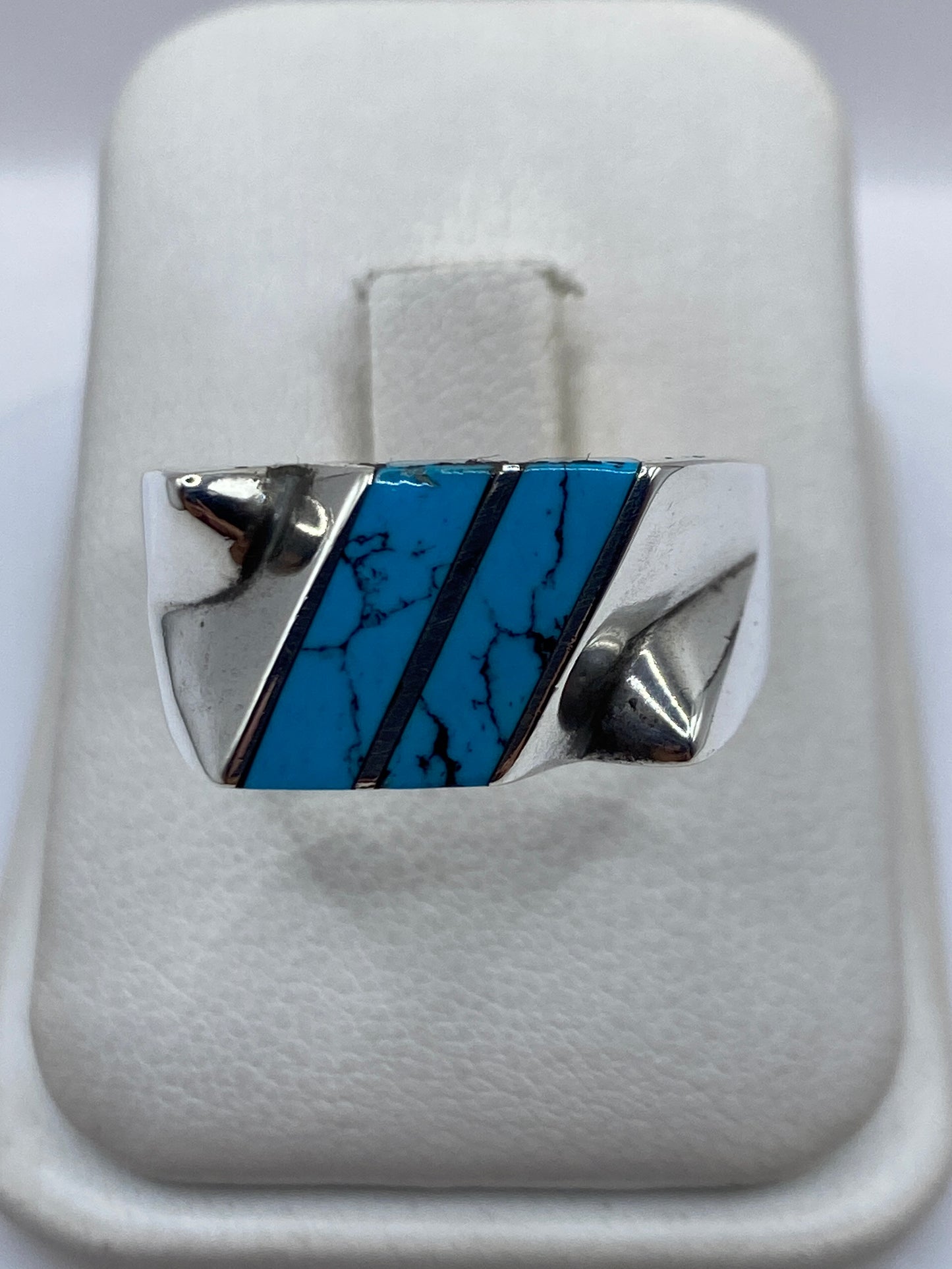 Anillo de plata con turquesa azul cielo engastada en diseño geométrico, vista frontal sobre fondo blanco