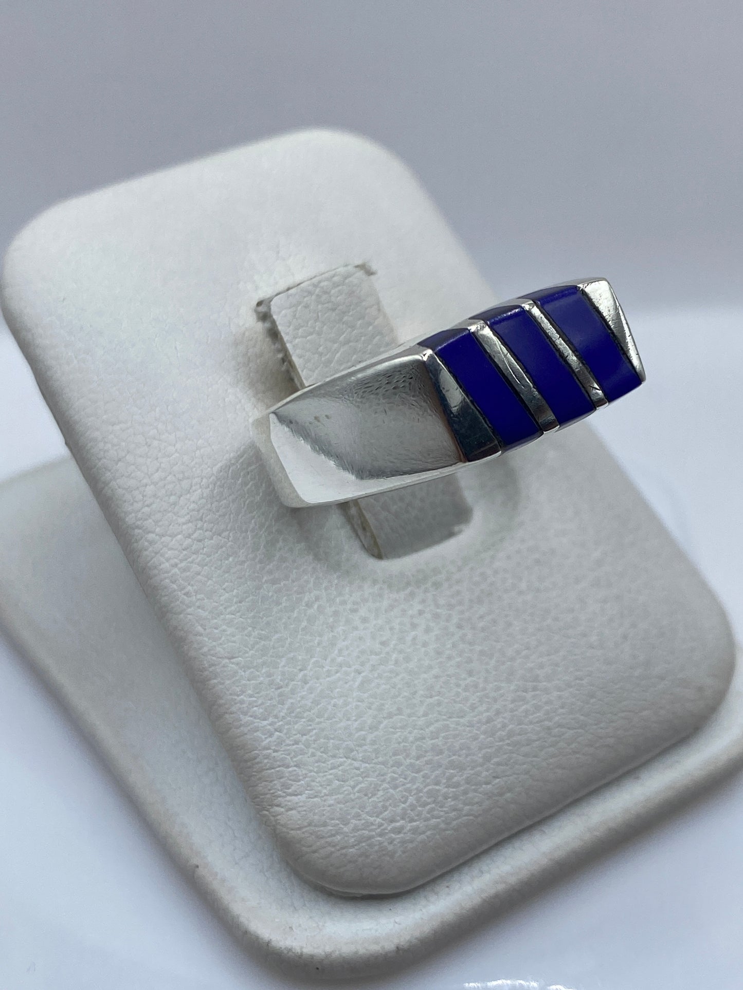 Detalle lateral del anillo mostrando la incrustación de piedra azul y el acabado pulido de la plata