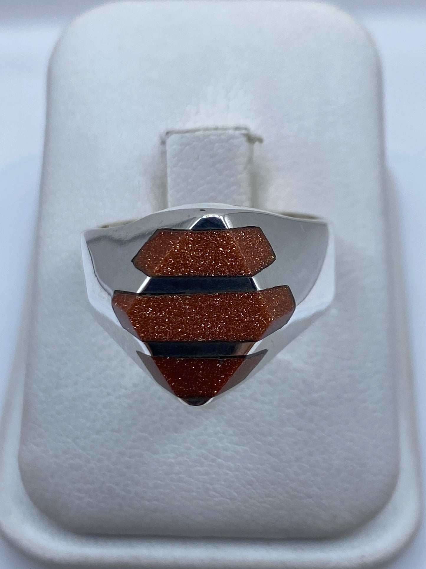 Anillo de plata escalonado con piedra incrustada visto desde arriba en caja blanca
