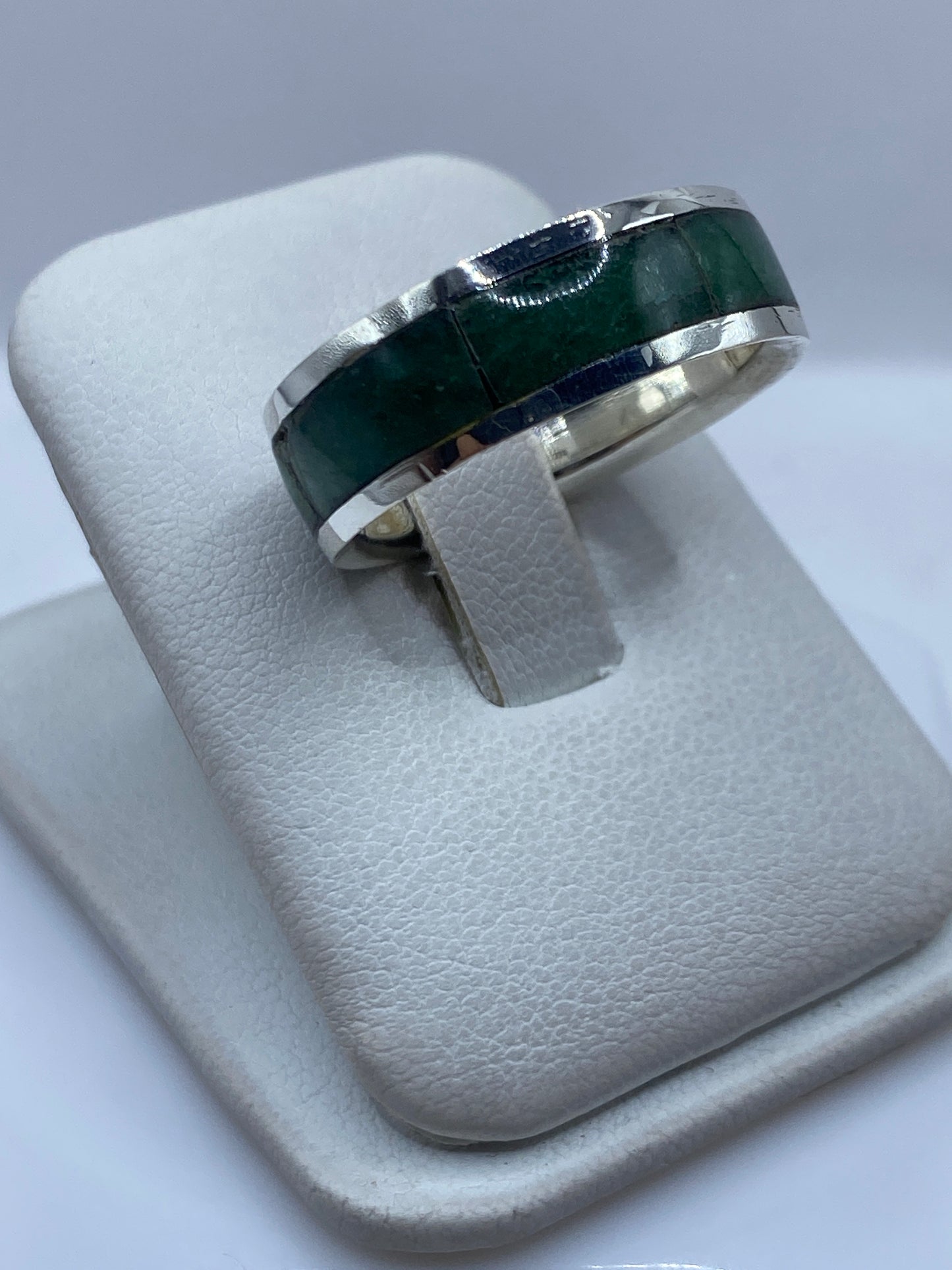 Anillo de plata con piedra verde desde el lateral, mostrando el engaste manual