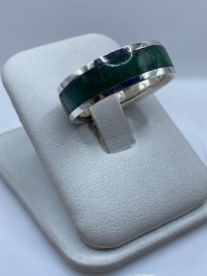 Anillo de plata con piedra verde desde el lateral, mostrando el engaste manual