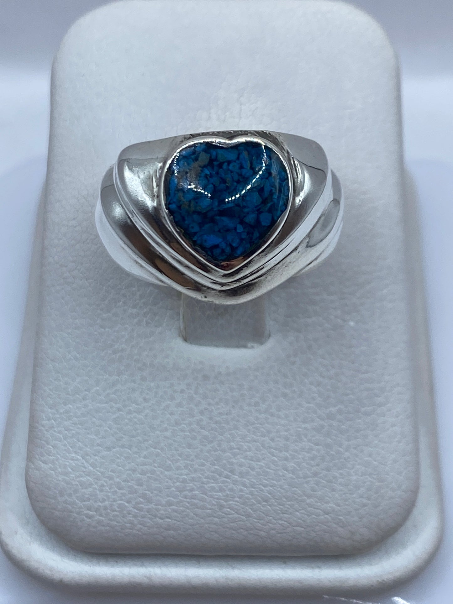 Anillo de plata con forma de corazón y piedra azul sobre fondo blanco