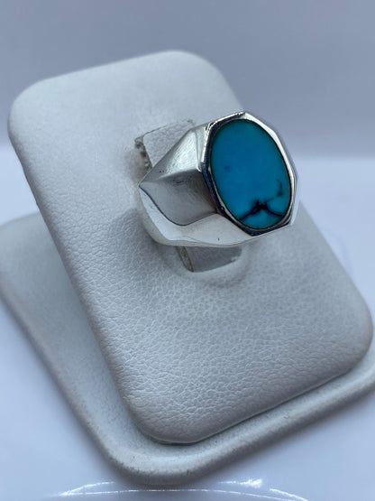 Detalle lateral del anillo de turquesa mostrando el engaste a mano y la montura de plata pulida