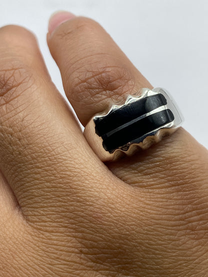 Anillo puesto en dedo mostrando el ónix negro brillante y el diseño geométrico