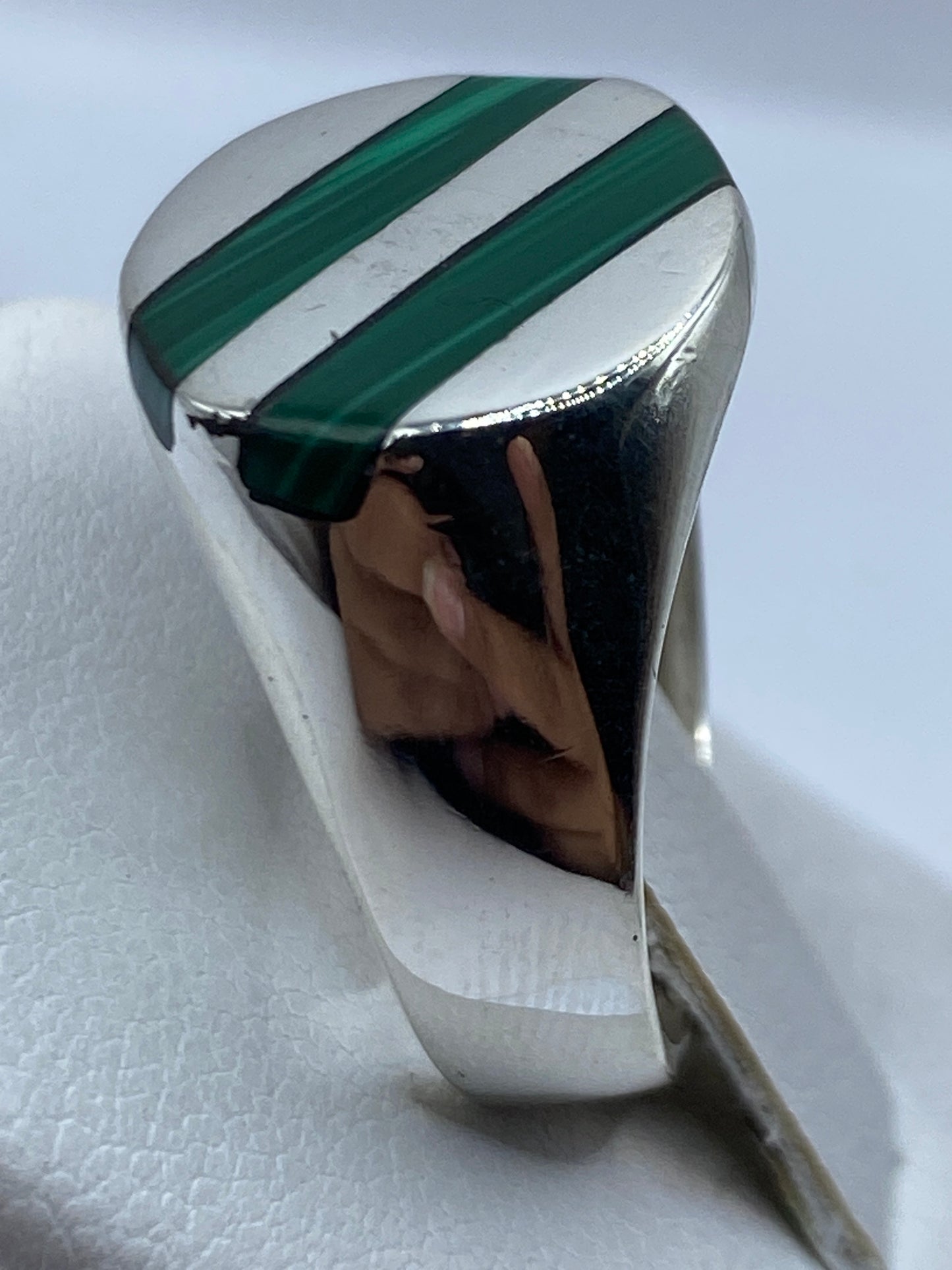 Anillo en la mano mostrando el verde profundo de la malaquita y el brillo de la plata