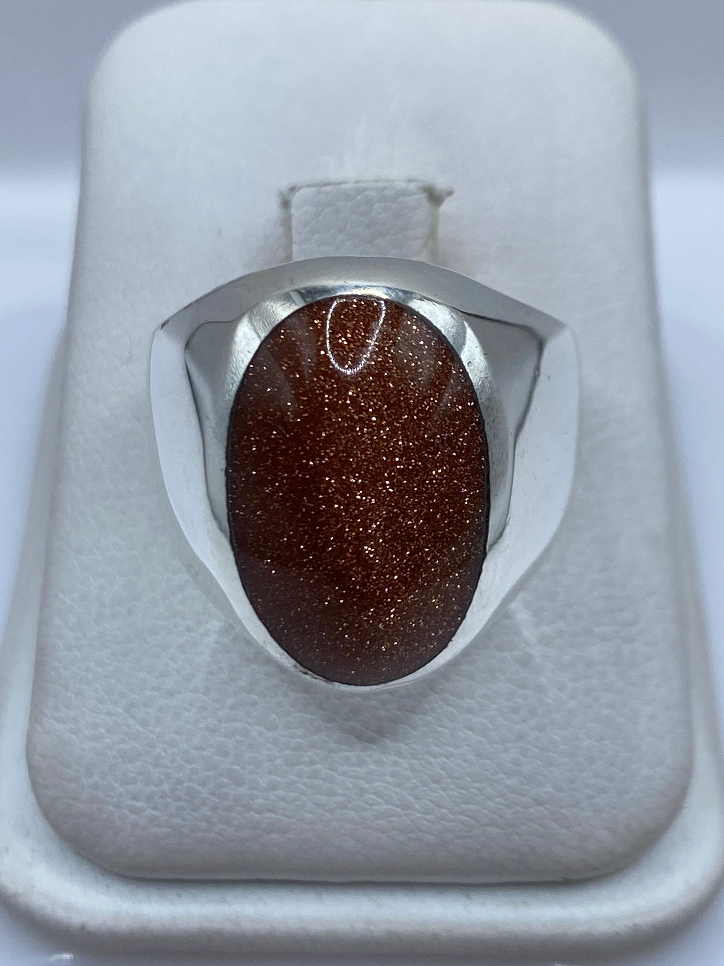 Anillo de plata .925 con piedra café engastada en la mano de una persona