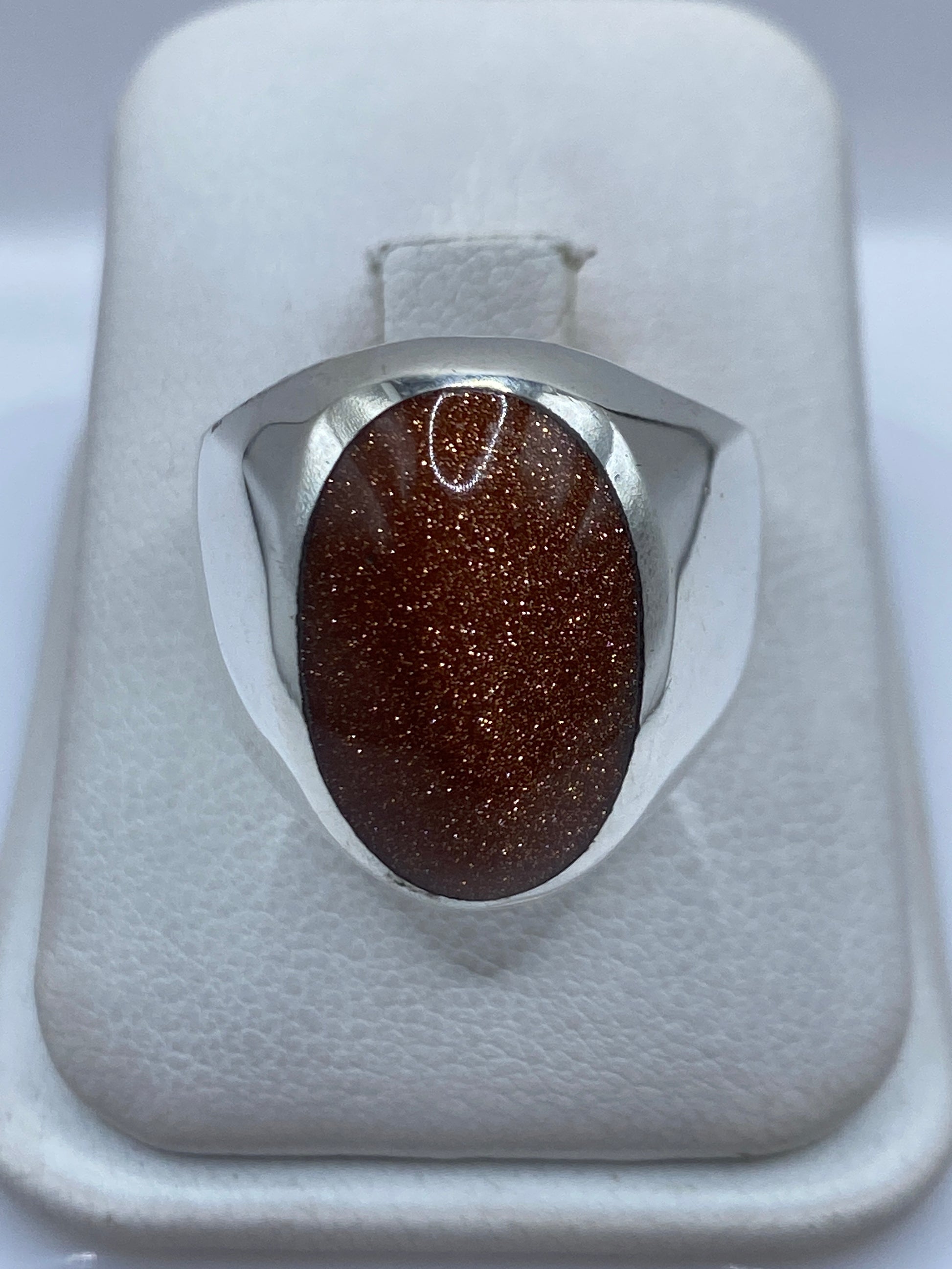 Anillo de plata .925 con piedra café engastada en la mano de una persona