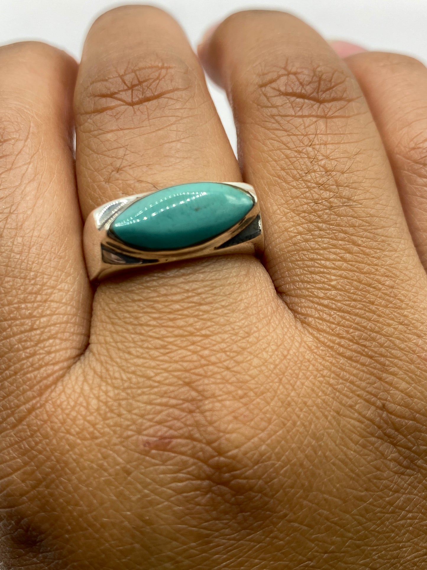 Anillo de plata con turquesa puesto en mano, mostrando el tono natural de la piedra
