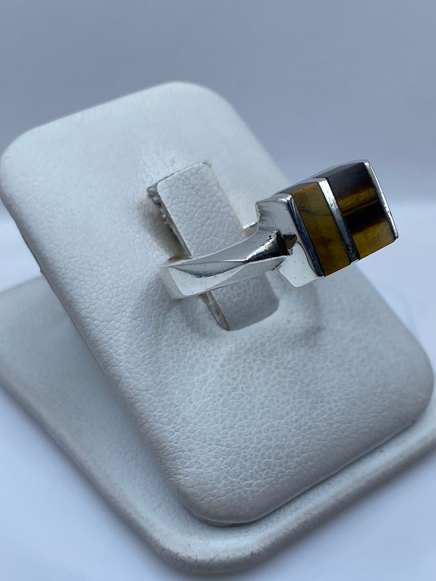Anillo de plata con piedra café tono profundo, visto de lado mostrando el perfil del engaste