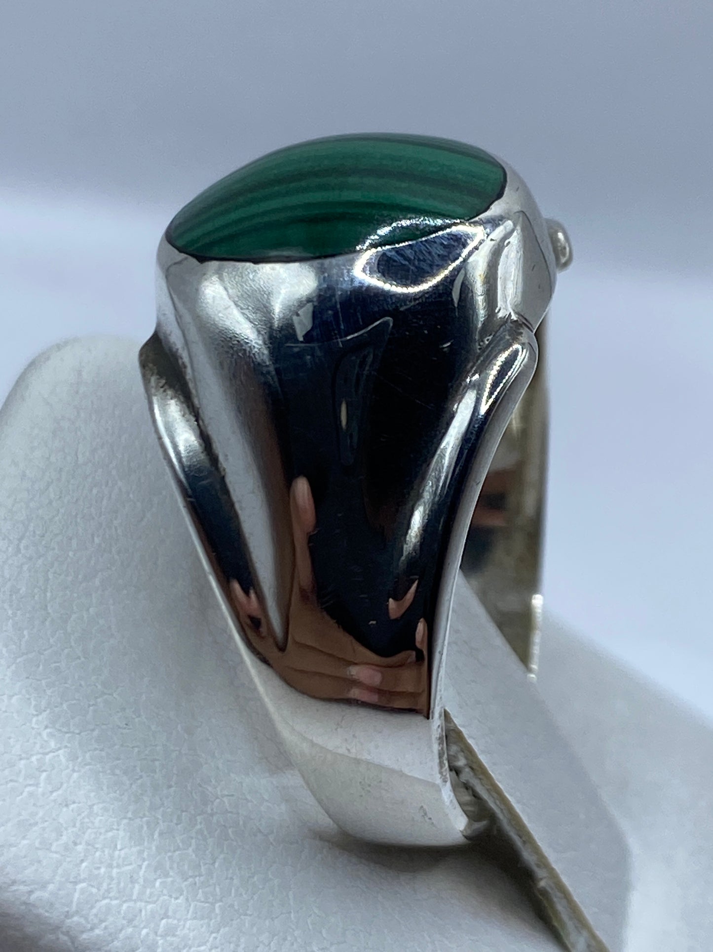 Detalle del anillo de plata con malaquita en dedo, mostrando las vetas naturales de la piedra