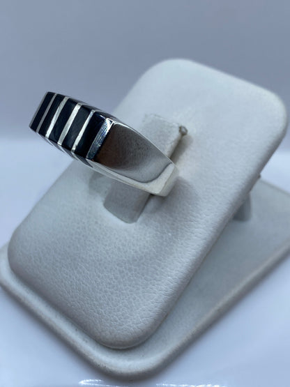 Anillo unisex de ónix negro en plata sobre la mano de una persona