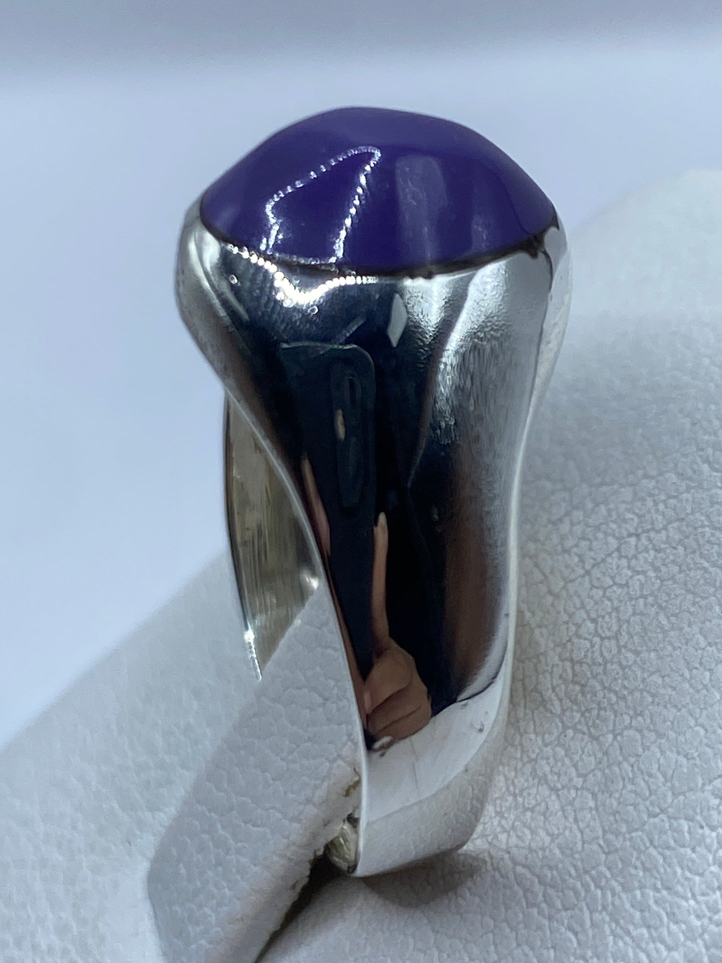 Anillo de piedra morada puesto en mano, vista frontal del brillo de la piedra