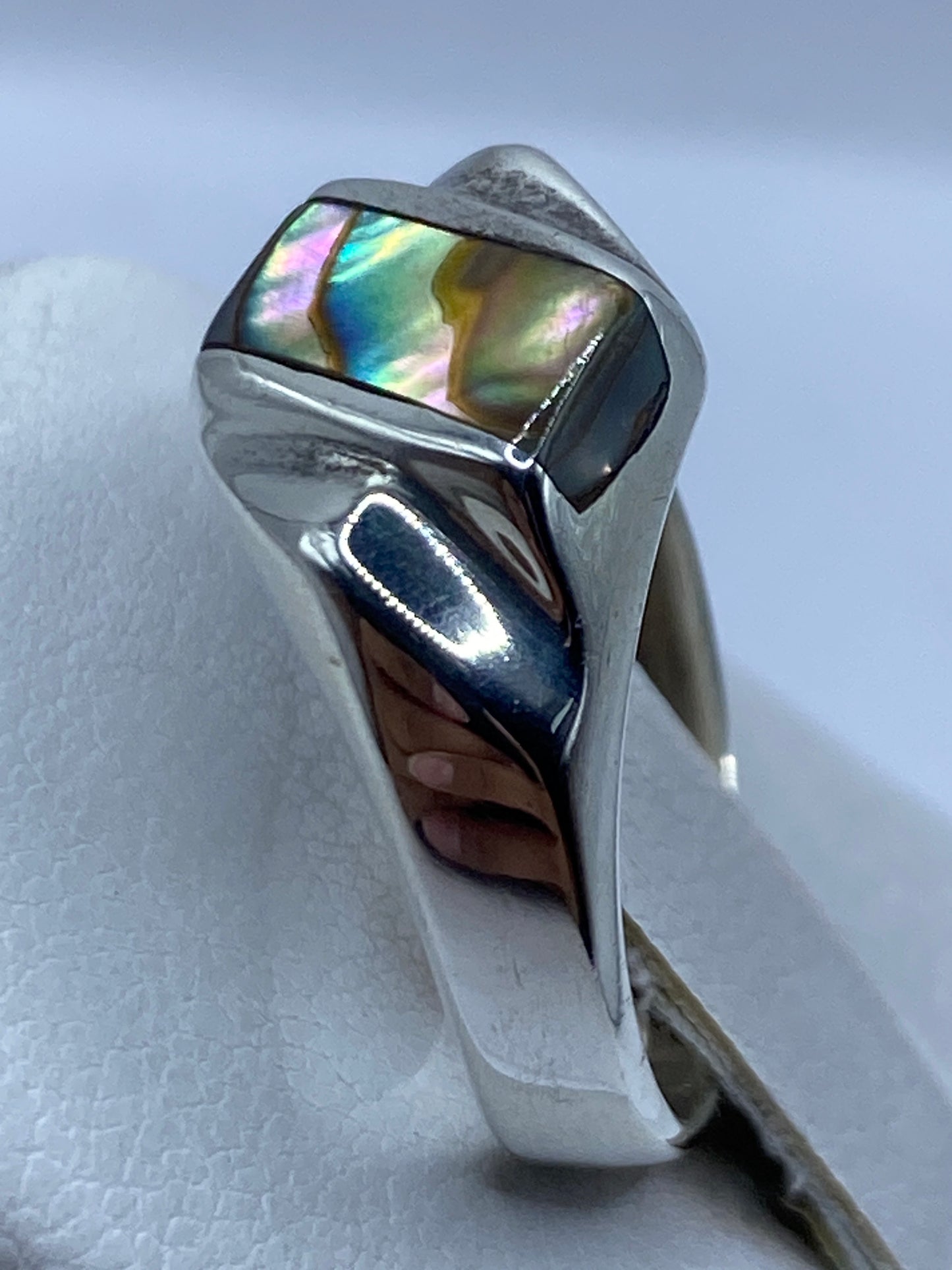 Anillo en la mano mostrando la piedra engastada con reflejos multicolor