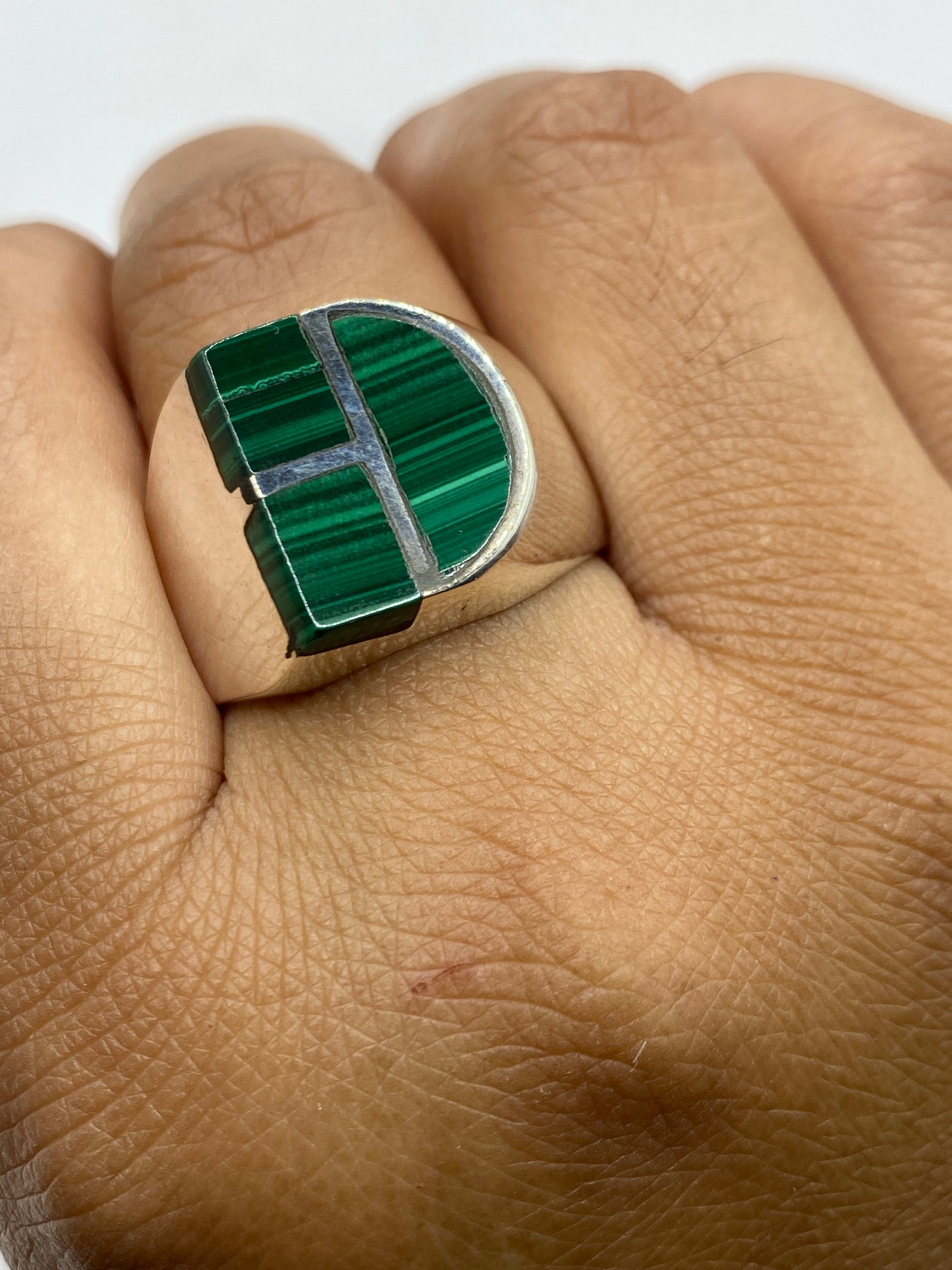 Anillo de malaquita en la mano mostrando el tamaño robusto y el acabado pulido