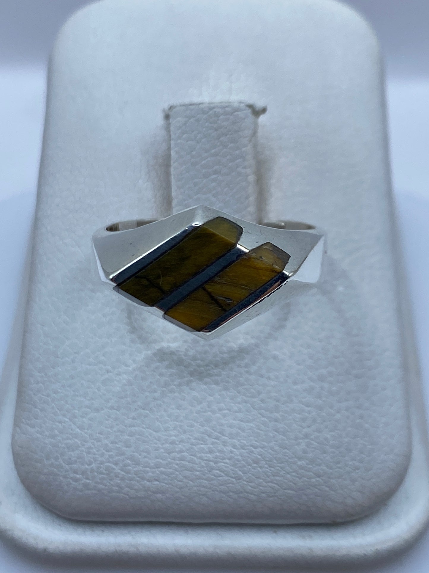 Anillo de plata con piedra café engastada a mano, vista frontal sobre fondo blanco