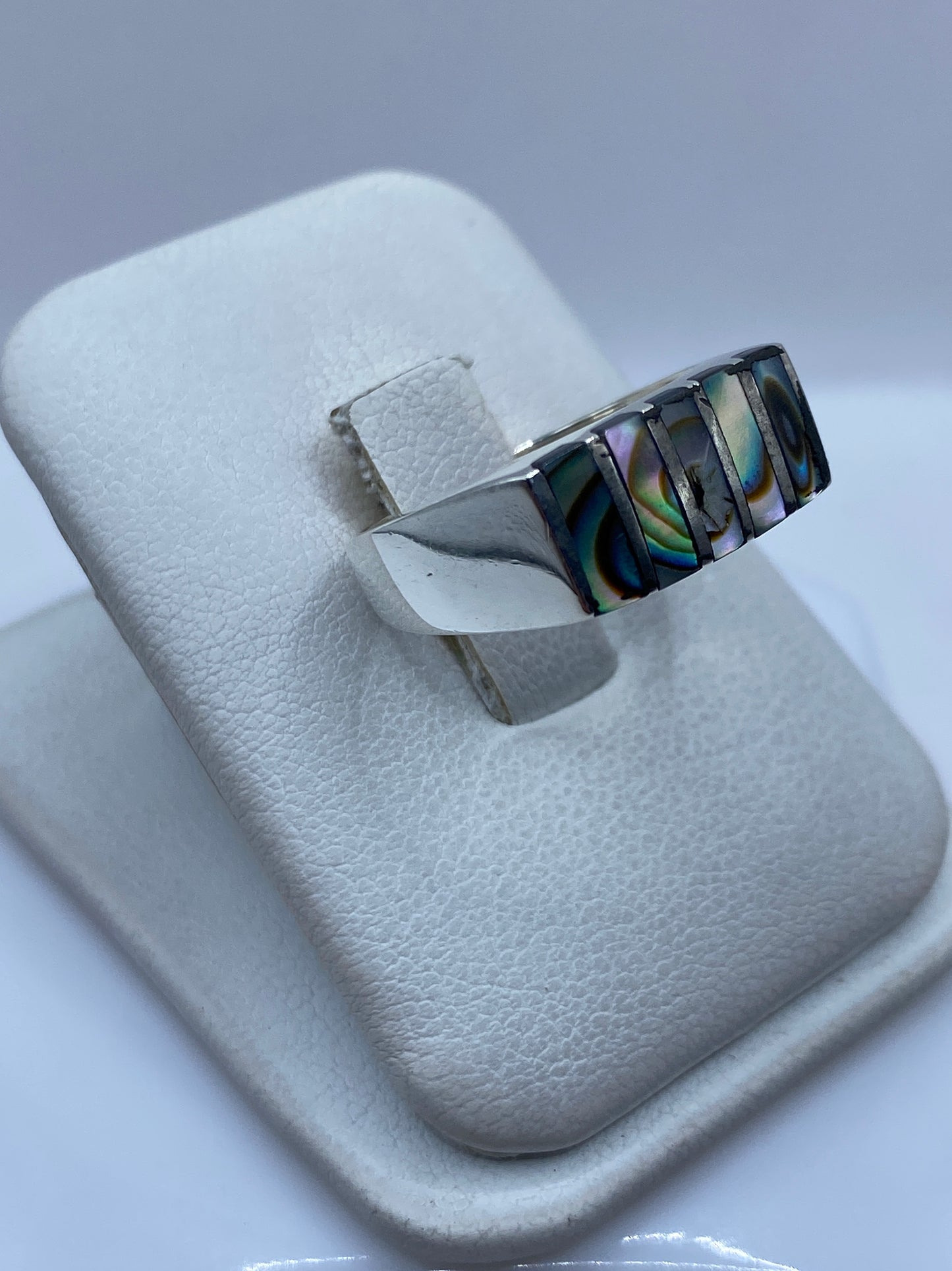 Vista frontal del anillo con piedras reflejando luz azul y verde