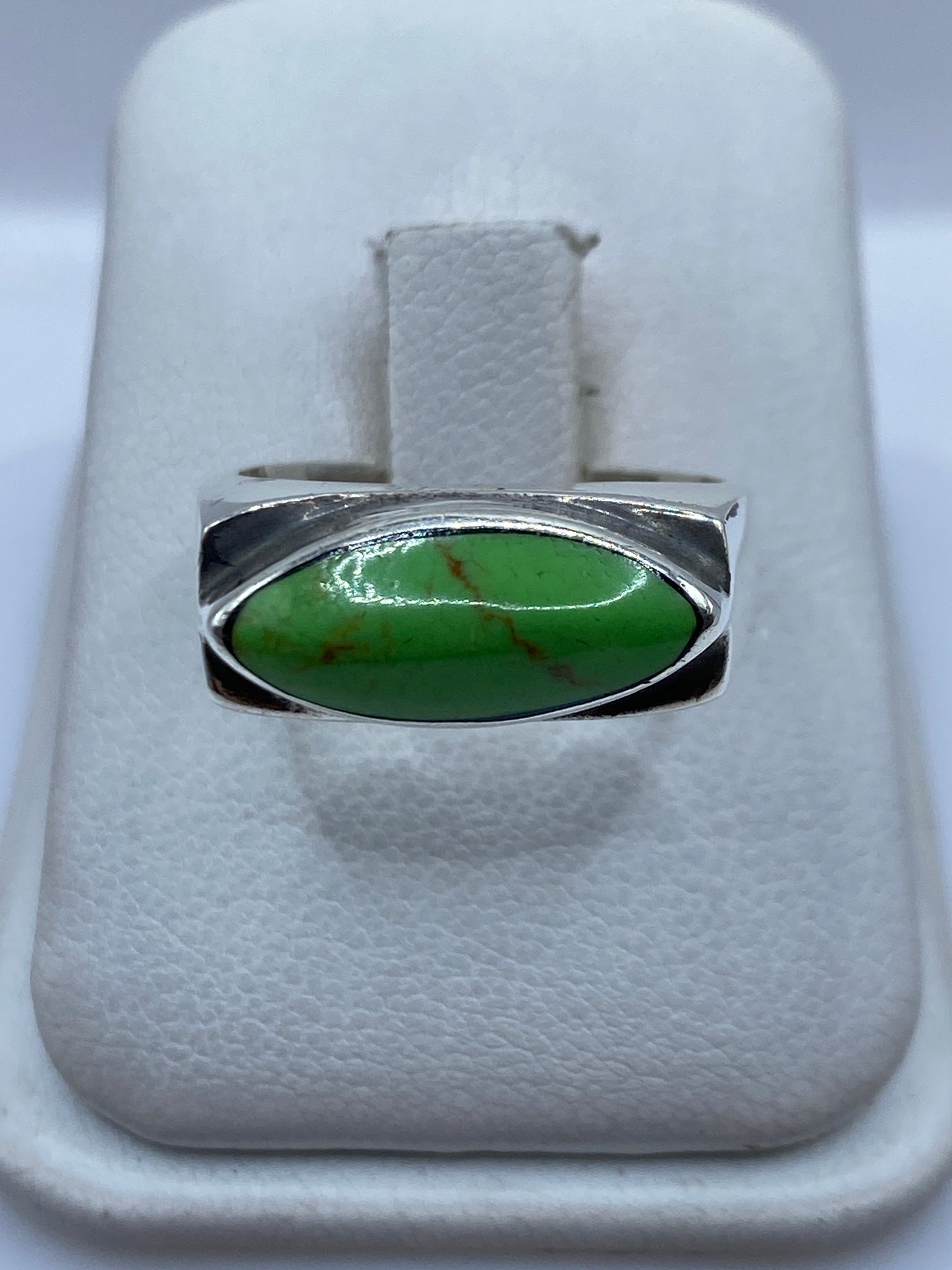 Anillo de plata minimalista con piedra verde engastada, visto de frente en estuche blanco