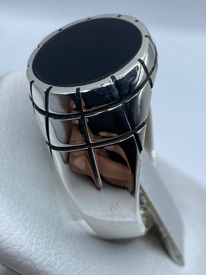 Anillo de ónix y plata en la mano de un hombre, mostrando el pulido espejo
