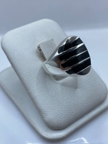 Anillo de ónix negro y plata en la mano, mostrando proporción y brillo
