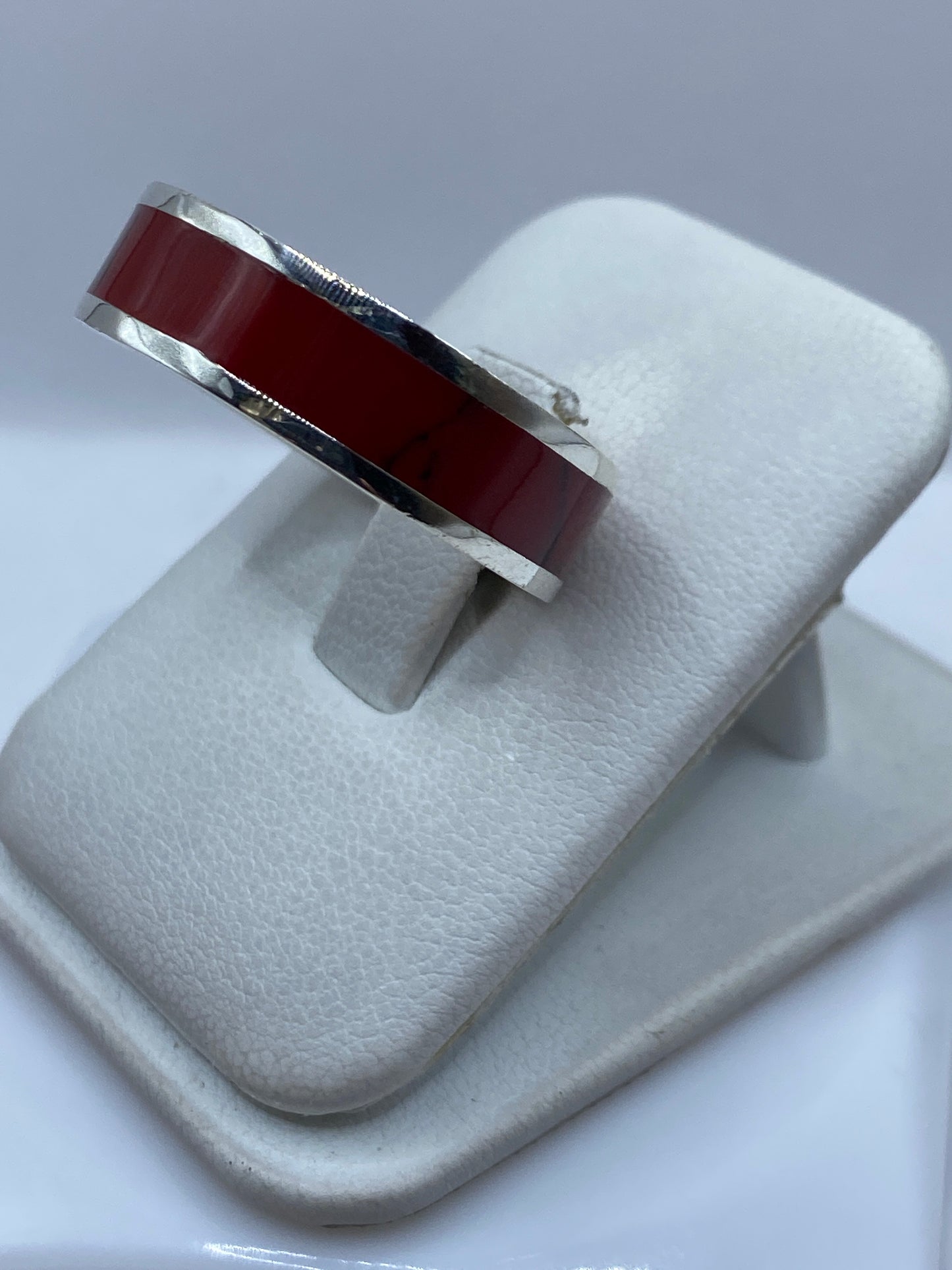 Detalle lateral del anillo mostrando el coral rojo y el acabado pulido de la plata