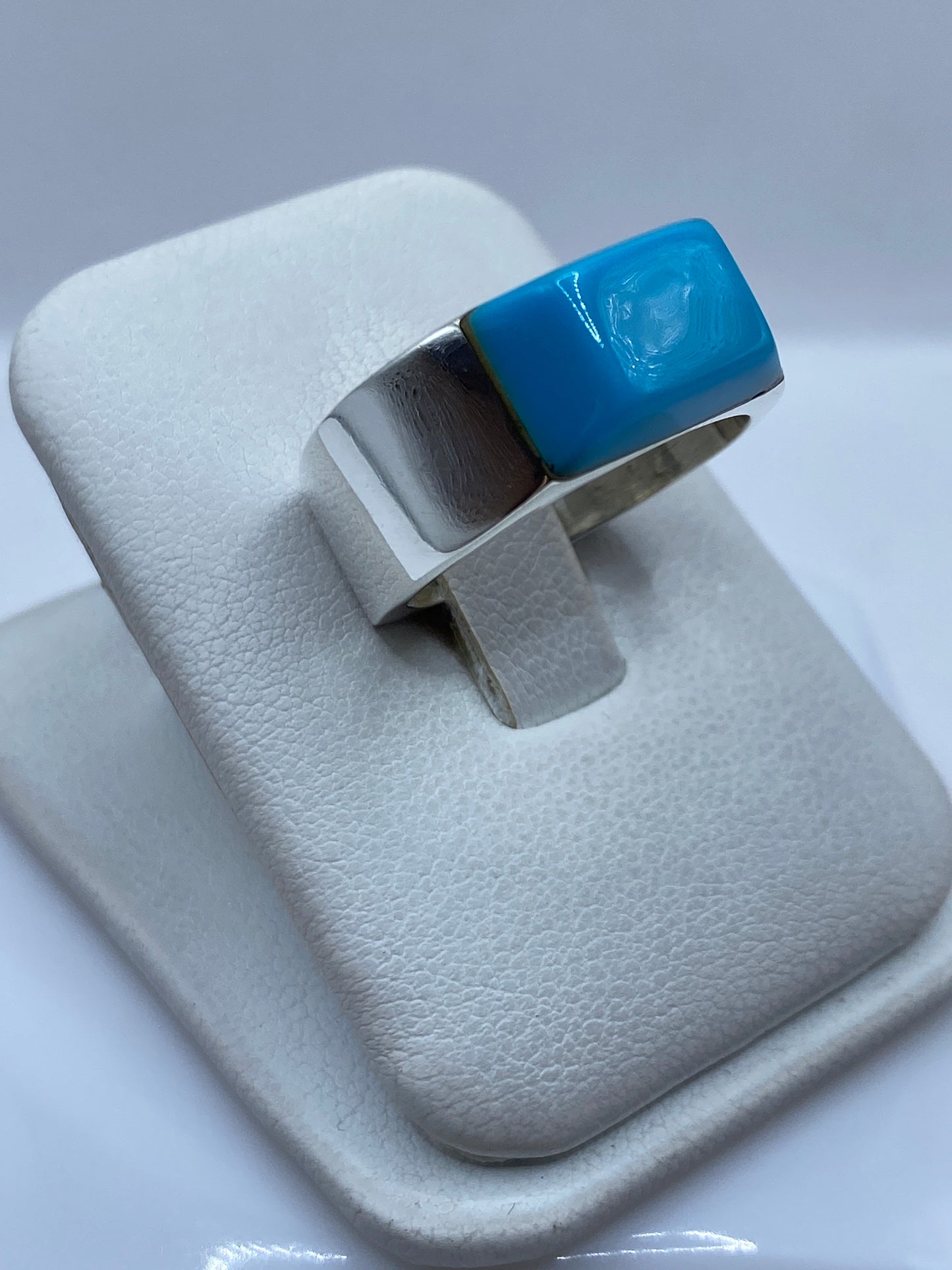 Detalle lateral del anillo mostrando el engaste a mano de la turquesa y la plata pulida