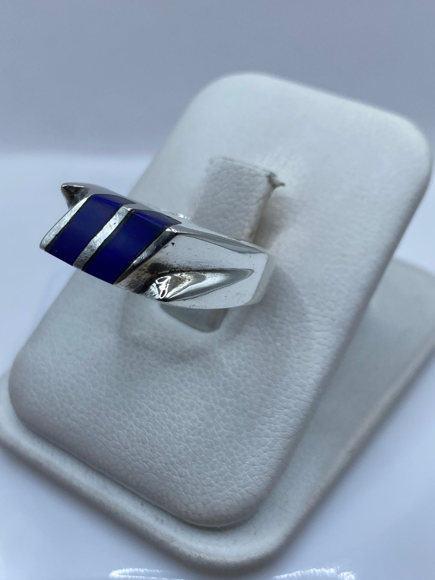 Anillo de plata con piedra azul vista lateral en dedo, diseño moderno versátil